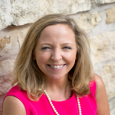 Workplace headshot of Karen Block , hearing instrument specialist with bright pink shirt and pearls