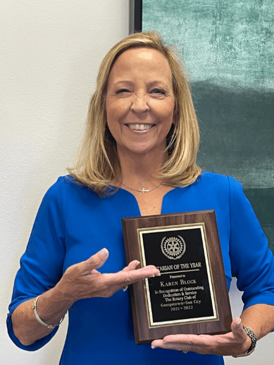 Karen Block in a blue top, she is holding up Rotarian of the year plaque that she was awarded